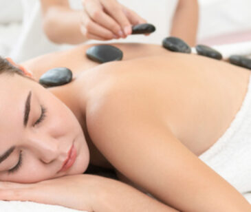 Hot stone massage treatment by therapist in spa.