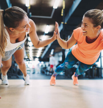 Two sporty girls doing push ups in gym