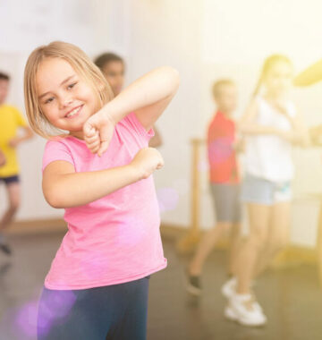 Smiling little girl training movements in children dance studio
